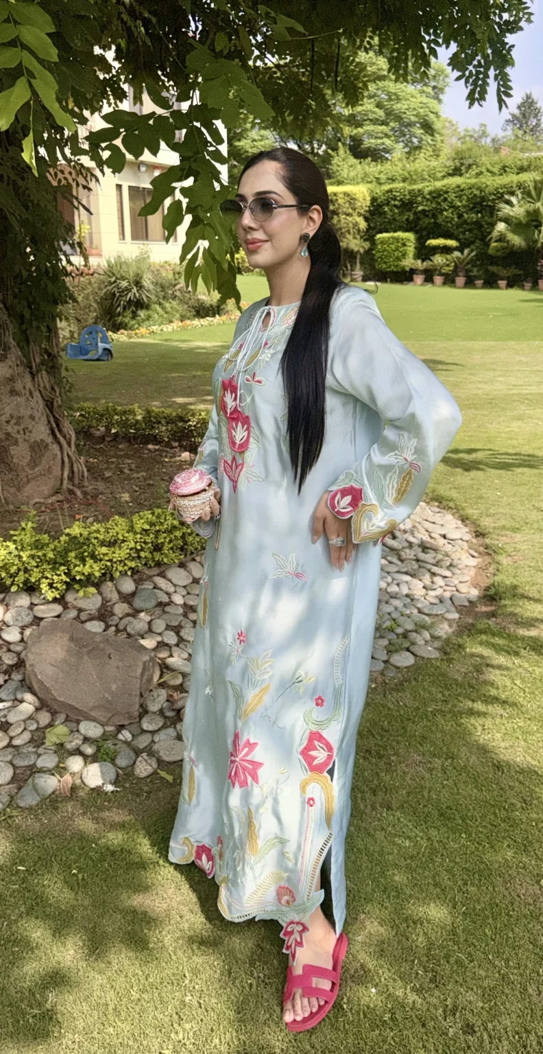 Side view of the pale aqua silk kaftan: fuchsia flowers down the front, mustard and sage leaves on the sleeve, and an openwork side slit above the scalloped hem